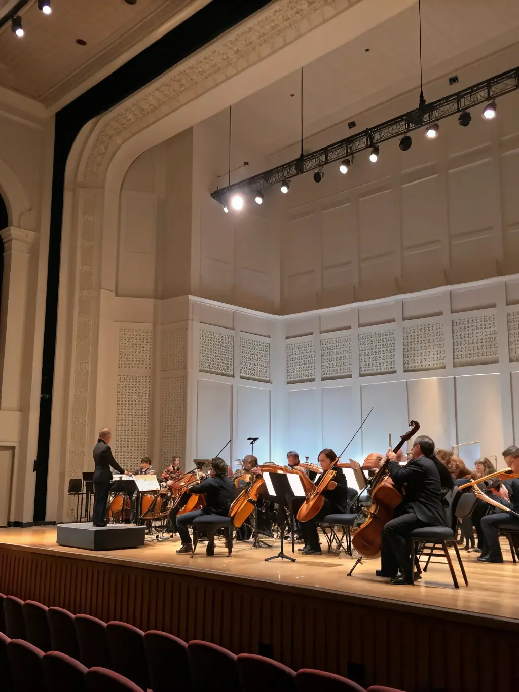 A spotlighted stage with a grand piano, young musicians in formal attire performing together, and a backdrop of shimmering gold and navy drapes, exuding a sense of celebration and achievement.